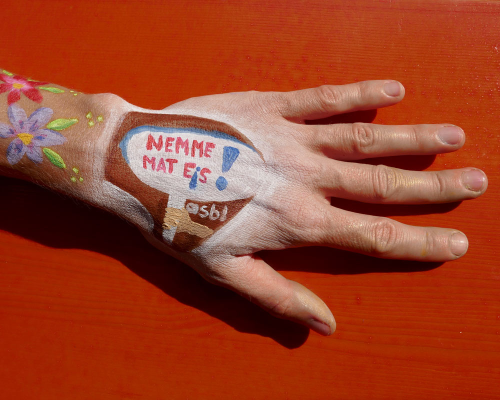 Hand mit dem Logo von Nëmme mat eis.