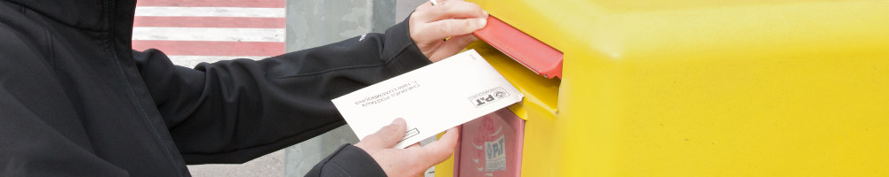 Ein Brief wird in einen Briefkasten eingeworfen.